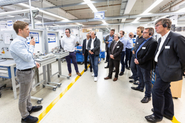 Jonas Hohmann, Production Engineering bei SMC Deutschland, führt die Besucher durch die hochflexible Produktion von SMC Deutschland am Standort Egelsbach. (Foto: SMC Deutschland GmbH)