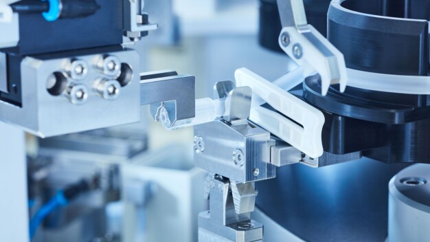 Montage von medizinischen Einweg-Schlauchsets mit der Lösung von Knoll Automation: Eine Klemme ist schon aufgeschoben, ein Luer-lock-Endstück wird gerade montiert. (Quelle: KNOLL Feinmechanik GmbH)