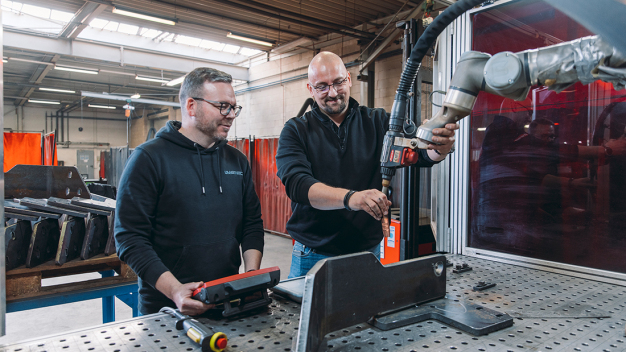 Fertigungsleiter Tony Meyer lässt sich von Fronius-Anwendungstechniker Andreas Plumeier zeigen, wie einfach das Teachen der Fronius SmartCell mit der Software SmartArt und dem SAEP-Handgriff funktioniert. (Bildnachweis: Christoph Große/pivopix im Auftrag von Fronius Deutschland GmbH)