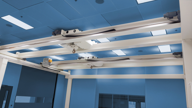 Abbildung 1 / Cleanroom crane with semi-automatic system and sway control, 5 tonnes load capacity per crane, ISO 5, both cranes can be operated in single and synchronised mode, application: aerospace industry. Abbildung 1 / Cleanroom crane with semi-automatic system and sway control, 5 tonnes load capacity per crane, ISO 5, both cranes can be operated in single and synchronised mode, application: aerospace industry.