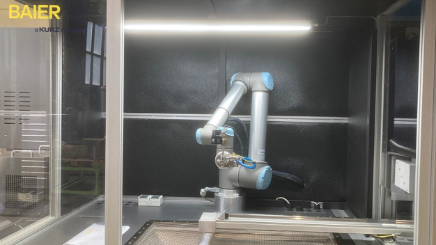 Angepasst an die Aufgabenstellung wird die Düse von einem Roboter über den zu reinigenden Bereich des Dekorteils geführt. (Bildquelle: BAIER GmbH + Co KG Maschinenfabrik) / Adapted to the task at hand, the nozzle is guided by a robot over the surface of the decorative part to be cleaned. (Image credit: BAIER GmbH + Co KG Maschinenfabrik)