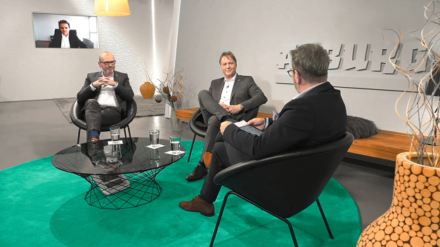 Die Experten Stefan Schrauf von PwC Deutschland (Bildschirm), Arburg-Geschäftsführer Guido Frohnhaus (l.) und Arburg-Entwicklungsleiter Werner Faulhaber (Mitte) diskutierten mit Moderator Guido Marschall das spannende Thema Lieferketten. (Foto: ARBURG) / The experts Stefan Schrauf from PwC Germany (screen), Arburg Managing Director Guido Frohnhaus (l.) and Arburg Development Director Werner Faulhaber (centre) discussed the exciting topic of supply chains with host Guido Marschall. (Photo: Arburg)