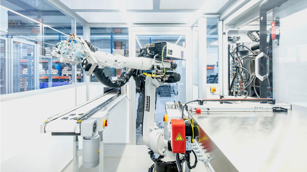Bei der Turnkey-Anlage sind zwei Reinräume kombiniert, das Teilehandling übernimmt ein in die Maschinensteuerung integrierter Sechs-Achs-Roboter. (Foto: PATRICK SAELY PHOTOGRAPHY) / Two clean rooms are combined in the turnkey system, and parts handling is performed by a six-axis robot integrated into the machine controller. (Photo: PATRICK SAELY PHOTOGRAPHY)