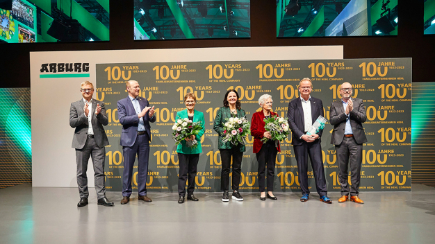 Emotionaler Abschluss: Im Namen aller Mitarbeitenden bedankten sich die Geschäftsführer Gerhard Böhm (links), Jürgen Boll (2. v. l.) und Guido Frohnhaus (rechts) am Ende der Jubiläumsfeier bei den geschäftsführenden Gesellschaftern Renate Keinath (3. v. l.), Juliane Hehl (4. v. l.) und Michael Hehl (2. v. r.). Standing Ovations gab es, als Gisela Hehl (3. v. r.) auf die Bühne gebeten wurde. (Foto: ARBURG) / Emotional conclusion: On behalf of all employees, Managing Directors Gerhard Böhm (left), Jürgen Boll (2nd from left) and Guido Frohnhaus (right) thanked Managing Partners Renate Keinath (3rd from left), Juliane Hehl (4th from left) and Michael Hehl (2nd from right) at the end of the anniversary celebration. There was a standing ovation when Gisela Hehl (3rd from right) was asked to come on stage. (Photo: ARBURG)