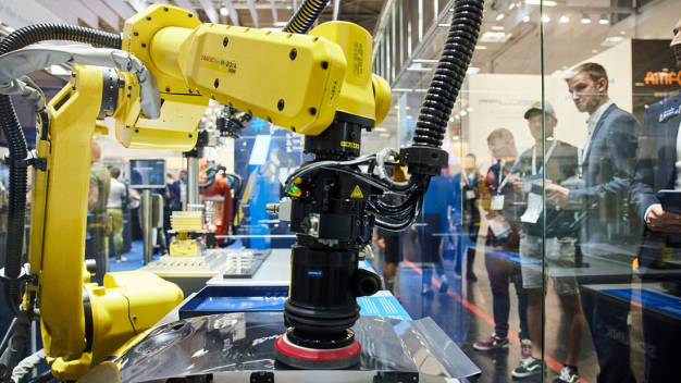 Besucher beobachten während der automatica 2022 einen Roboter bei seiner Arbeit. / Visitors observe a robot at work during automatica 2022.