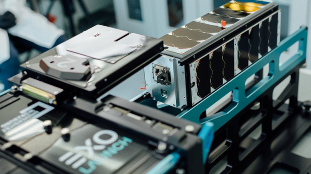 Der CubeSat bei der Integration in den Auswurfcontainer. Auf der Stirnseite ist der Pyramidenförmige Laser-Ranging Reflektor der EPISODE Nutzlast zu sehen. 