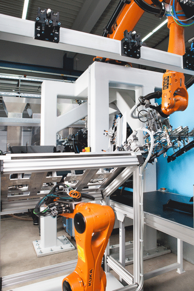 Zwei Kuka Roboter arbeiten an einer Spritzgießmaschine Hand in Hand. (Foto: KUKA) / Two KUKA robots work on an injection molding machine by hand in hand. (Photo: KUKA)