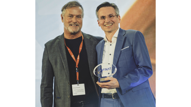Branchenexperte Corey Reardon, CEO des Marktforschungs- und Beratungsunternehmens AWA Alexander Watson Associates, überreicht den FINAT-Innovationspreis an Dr. Jens Vor der Brüggen, Leiter Forschung + Entwicklung bei der Schreiner Group. © Schreiner Group / Industry expert Corey Reardon, CEO of the market research and consulting firm AWA Alexander Watson Associates, presents the FINAT Innovation Award to Dr. Jens vor der Brüggen, Head of Research & Development at Schreiner Group. © Schreiner Group