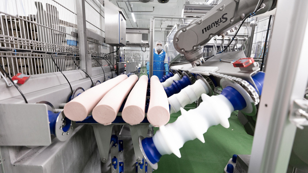 Mit seinem Vierfachgreifer holt der Stäubli TX200 die 12 kg schweren Wurstkaliber an definierter Bereitstellungsposition ab. (Copyright: Stäubli Tec-Systems GmbH Robotics) / Using its quadruple gripper, the Stäubli TX200 picks up the 12-kg sausages from a defined position. (Copyright: Stäubli Tec-Systems GmbH Robotics)