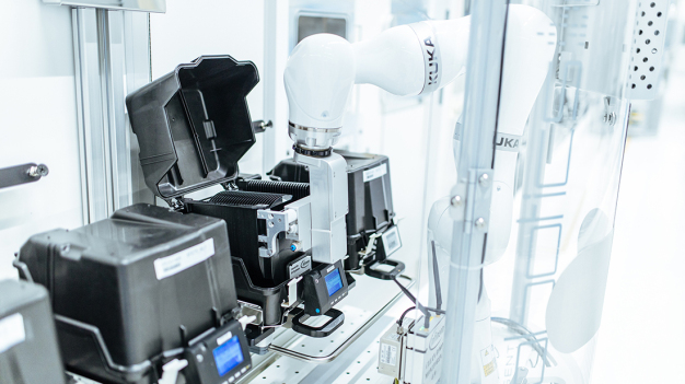 Die Reinraum-Roboter transportieren schwarze Kassetten voller Silizium-Wafer zu den einzelnen Bearbeitungsschritten. / The cleanroom robots transport black cassettes full of silicon wafers to the individual processing steps.