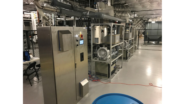 Figure 2: Two VHP generators and skids installed in the mechanical space. A 50-gallon drum of peroxide can be seen in the foreground. The manifold that delivers VHP to the different cleanroom suites can be seen top center (white).