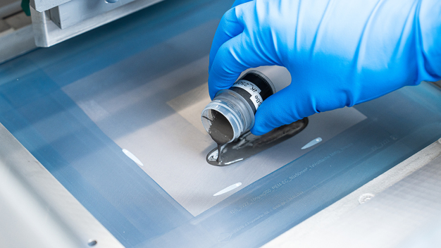 Paste bestehend aus Titanpulver, Lösemittel und Additive wird auf dem Drucksieb aufgetragen. Im Anschluss wird die Paste mit dem Druckrakel durch das Sieb als dünne mikroporöse Schicht auf ein Titanfasersubrat aufgebracht. © Fraunhofer ISE/Joscha Feuerstein / A paste consisting of titanium powder, solvent and additives is applied to the pressure screen. The paste is then applied through the screen as a thin microporous layer onto a titanium fibre substrate using a squeegee. © Fraunhofer ISE/Joscha Feuerstein