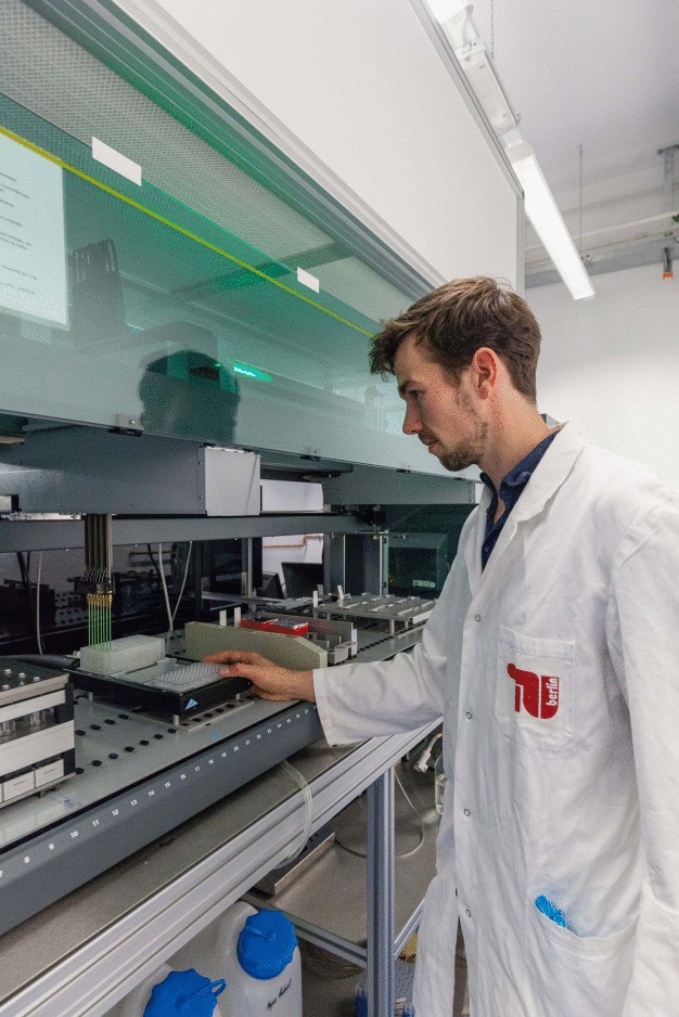 Laborleiter Florian Glauche setzt einen Probenhalter mit Lösungen ein, die in die Bioreaktoren gefüllt werden. (© TU Berlin/PR/Felix Noak)