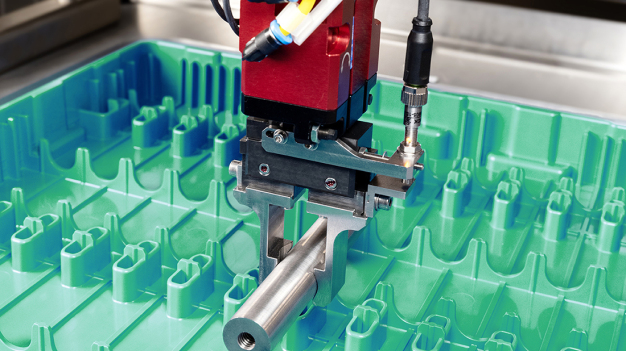 Ein Autoinjektor wird aus einem Tray entnommen – hier gezeigt anhand eines Muster-Bauteils. (Quelle: PIA Automation) / An auto-injector is removed from a tray – shown here using a sample component. (Source: PIA Automation)