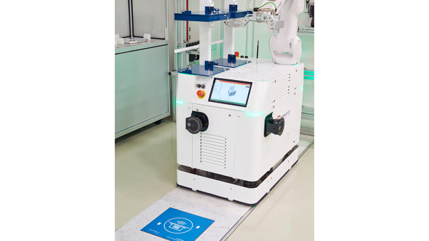 Chargement en cours : Le robot mobile recharge son énergie via un panneau de recharge situé devant la station de manutention et continue de fonctionner sans pauses de recharge séparées. (Source : Fabmatics GmbH, Photographe : Sven Claus (FotograFisch))